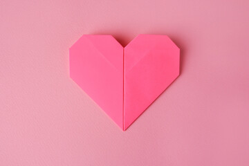 Origami art. Paper heart on pink background, top view