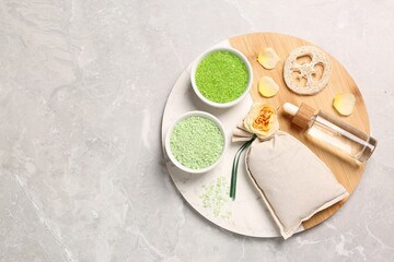 Bowls with sea salt and different spa products on light grey marble table, flat lay. Space for text