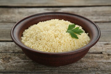 Tasty couscous with parsley on wooden table, closeup