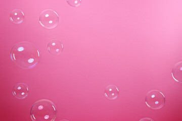 Many beautiful soap bubbles on pink background