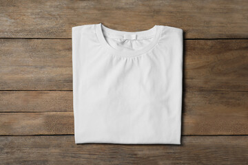 Stylish white T-shirt on wooden table, top view - obrazy, fototapety, plakaty
