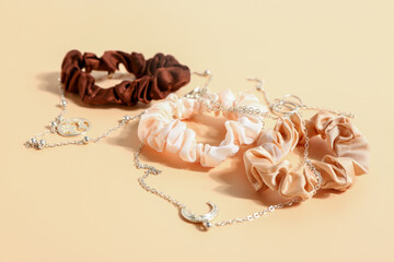 Silk scrunchies and necklaces on color background