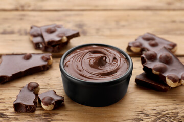 Chocolate pieces and bowl of sweet paste on wooden table