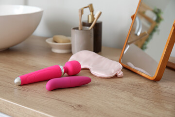 Sex toys with sleeping mask and mirror on table in bathroom, closeup