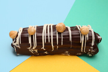 Delicious chocolate eclair with hazelnuts on colorful background