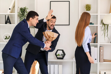 Young men with paper bag playing a prank on their colleague in office. April Fools' Day celebration