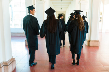 Rear view of graduates walking on university campus