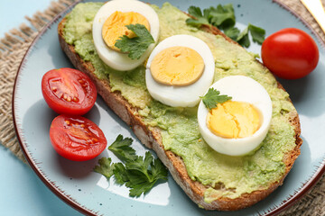 Delicious toast with avocado, boiled eggs, tomatoes and parsley in plate, closeup