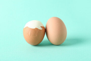 Peeled and unpeeled boiled eggs on turquoise background