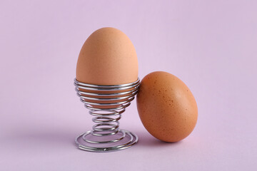 Holder with delicious boiled egg on lilac background