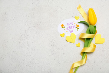 Composition with greeting card, tulip flower, ribbon and origami hearts on light background. Mother's Day celebration