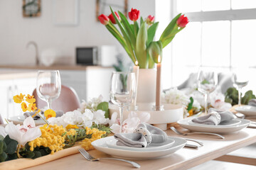 Beautiful table setting for International Women's Day celebration with different flowers in interior of light room