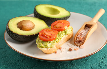 Plate with delicious avocado toast on green background