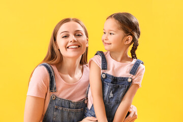 Happy little girl with her mother on yellow background, closeup