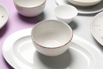 Fototapeta na wymiar Clean ceramic dishes on lilac and grey background