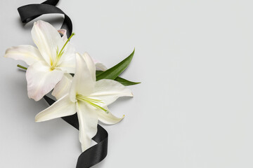 Black funeral ribbon and beautiful lily flowers on white background - obrazy, fototapety, plakaty