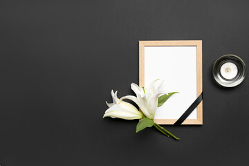 Blank funeral frame, lily flowers and burning candle on dark background