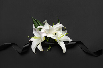 Black funeral ribbon and white lily flowers on dark background - obrazy, fototapety, plakaty