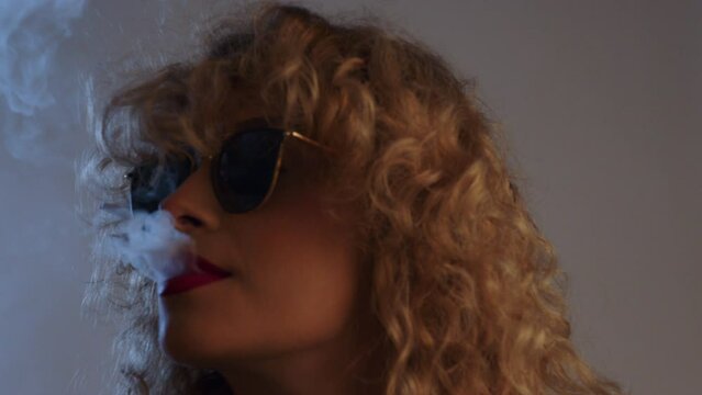 portrait of a woman with sunglasses smoking vape