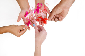 Group of hands holding pink ribbon for breast cancer awareness. People take the ribbon from the woman's hand