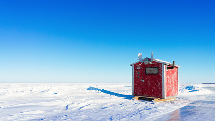 Charming Winter Scene of a Red Fishing House with Authentic Moose Horns: Ideal for Cozy, Seasonal, and Rustic-Themed Projects on Stock