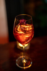 A glass of red wine and a lime wedge is on a table next to a candle.