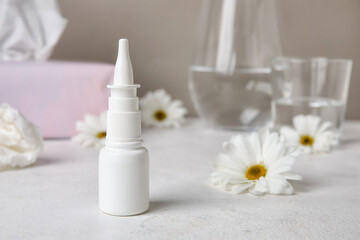 Fototapeta na wymiar Nasal drops with flowers on white table. Seasonal allergy concept