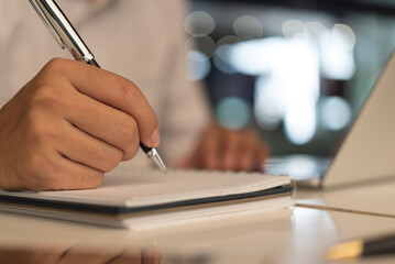 man hands with pen writing on notebook in the office.learning, education and work.writes goals,...