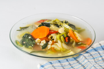 Cap cay, consists of various vegetables including mustard greens, cauliflower, carrots, served on a small plate with a napkin isolated on a white background.