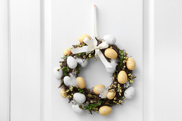 Easter wreath hanging on white wooden door, closeup