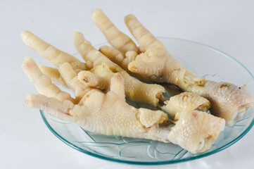 Fototapeta na wymiar Boiled chicken feet as a soup mixture is served on a small plate isolated on a white background