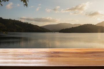 Empty wooden table with lake and sunset background