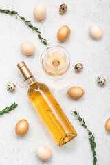 Composition with bottle of wine, glass, Easter eggs and eucalyptus branches on light background