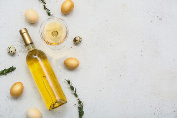 Composition with bottle of wine, glass, Easter eggs and eucalyptus branches on light background