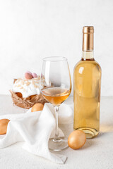 Bottle of wine, glass, Easter eggs and cake on light background