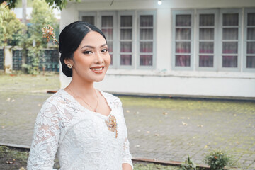 A young Indonesian woman with a happy successful expression wearing a white kebaya. Kartini's Day...