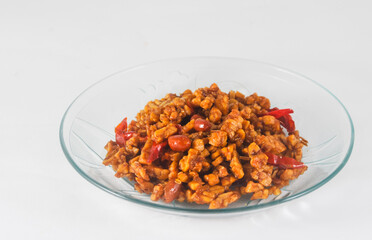 sliced tempeh fried dry with chilies and peanuts or orek tempe served on a small plate isolated on a white background
