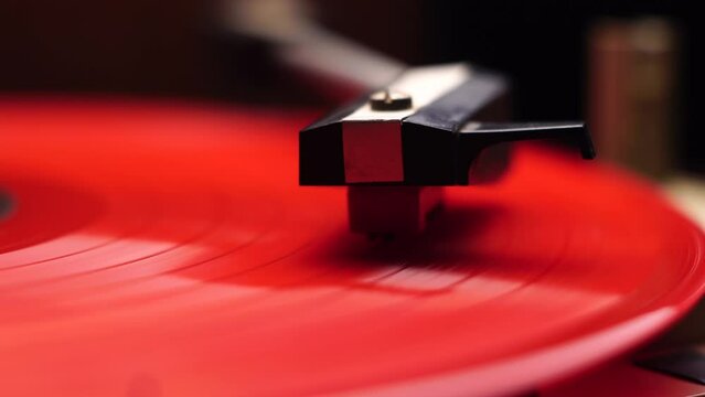 Close Up of Gramophone Needle and Headshell on Vintage Red Vinyl Record