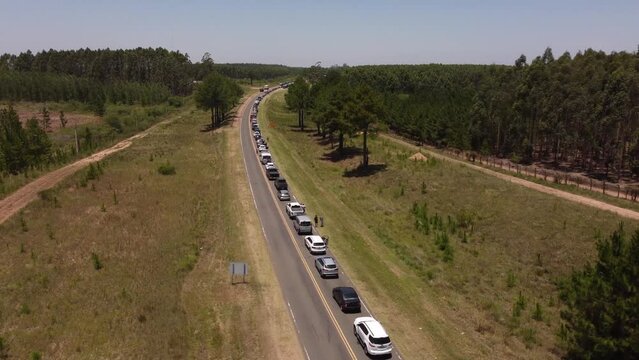 Aerial flyover rural road with traffic jam at border between Argentina and Uruguay during sunny day