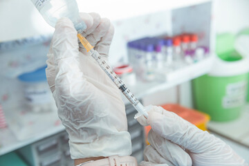 A nurse in draws corticosteroid from a vial into a syringe. Preparing to inject opioid pain medication. Hospital or ER scene.
