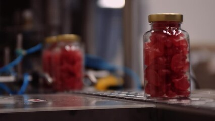 Red gummy multivitamin supplements bottled and on conveyor belt - automated process