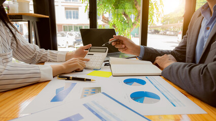 Team of professional business partners holding pen pointing at financial graph document, calculating analysis and strategy consulting. Meeting, brainstorming at office, teamwork concept.