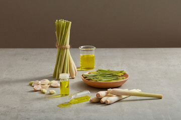 A bunch of lemongrass (Cymbopogon citratus) standing next to wooden dish of lemongrass. Glass jars...
