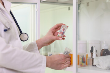 Doctor puts box of pills on shelf in office.