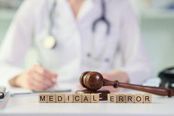 Words medical errors collected from wooden cubes with judge's gavel on table.
