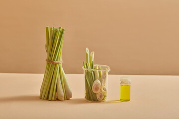 A bunch of lemongrass standing next to a glass jar of lemongrass. An empty label bottle containing essential oil extracted from lemongrass. Product mockup. Good for people’s health