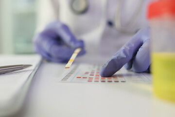Close-up of doctor checking medical test results at desk in medical clinic.