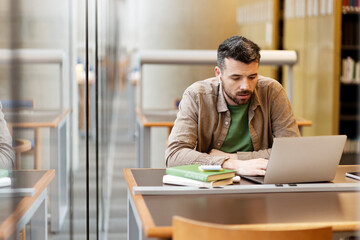 Pensive middle aged latin student using laptop computer studying, learning language, exam...