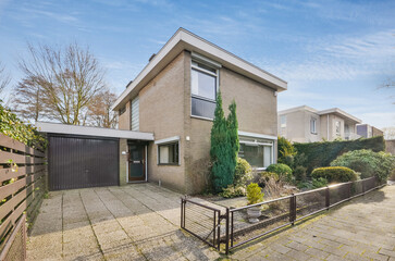 a house in the middle of an urban neighborhood, with a gated driveway leading up to the front door