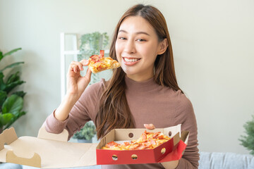 Fototapeta premium Happy meal with fast food, pleasure asian young woman, girl hold piece, enjoy eating delicious slice of pizza having takeaway at home relaxing resting, like taste good appetite, snack in lunch, dinner